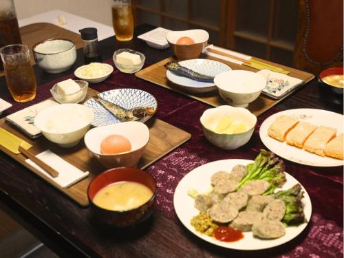 a table with plates and bowls of food on it at 古民家サウナandバーベキュー TK亭 in Ichihara