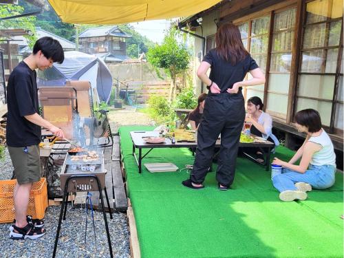 a group of people cooking food at a table at 古民家サウナandバーベキュー TK亭 in Ichihara