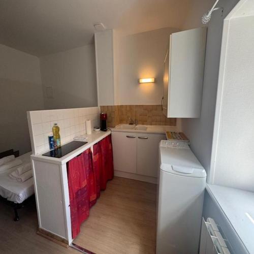 a small kitchen with red cabinets and a white refrigerator at Studio Le Verdun et La République in Tournus