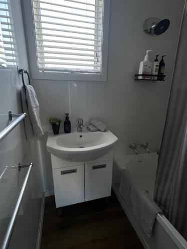 a white bathroom with a sink and a bath tub at Relax at Jollie-Cozy 3-Bedroom Home, Central Twizel in Twizel