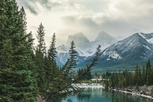 a river with trees and mountains in the background at Alpine Village Condo by Canadian Rockies Vacation Rentals in Canmore