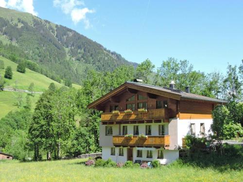 a house in a field with mountains in the background at Apartment in Fusch an der Glocknerstraße in nature in Fusch an der Glocknerstraße