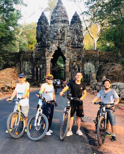 a group of people on bikes in front of an arch at Chamraoen’s Home in Siem Reap
