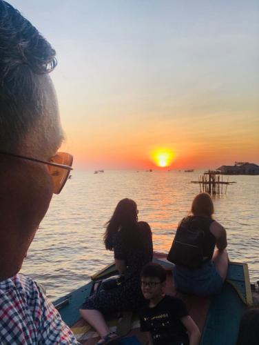 a group of people sitting in a boat watching the sunset at Chamraoen’s Home in Siem Reap