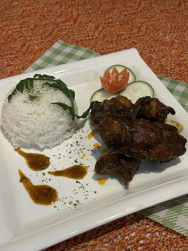 Kyle's Bed and Breakfast DMall Boracay في بوراكاي: طبق طعام يحتوي على أرز ولحم وطماطم