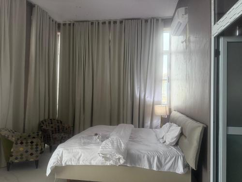 a bedroom with a white bed and a window at The Lawton in Cape Coast