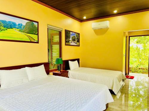 two beds in a room with yellow walls at Hidden Rock Tam Coc in Vũ Lâm