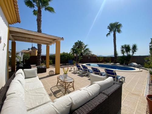 a patio with a couch and chairs and a pool at Casa Vida La Vida in Mazarrón
