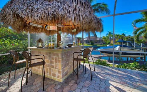 a bar with two chairs and a straw umbrella at Villa Viscaya in Shell Point Village