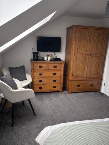 1 dormitorio con TV, vestidor y silla en Dylchrikie House, en Barnstaple