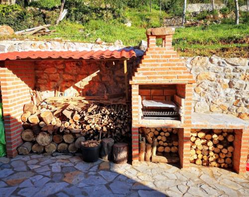 a building with a pile of logs and a fireplace at La casina del cabrajigo in Cangas de Onís