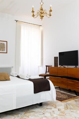 a white bedroom with a bed and a television at B&B Don Alessandro in Surbo