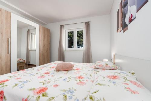 a bedroom with a bed with a floral bedspread at Holiday House Laetitia with pool in Banjevci