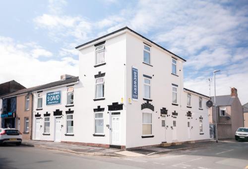 a white building on the corner of a street at The Old Brewery - A St David Aparthotel in Barrow in Furness