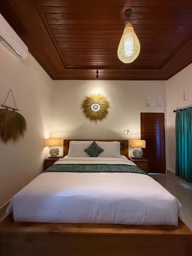 a bedroom with a white bed with a wooden ceiling at D'Labake Guest House in Sidemen