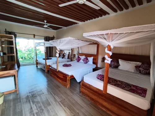 a bedroom with two beds and a large window at DOGO E ILARIA Bed & Breakfast in Nungwi