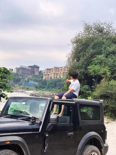 a man sitting on the back of a truck at Aloha Apartments by blissful Ganges in Rishīkesh