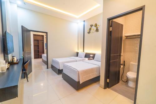 a hotel room with two beds and a toilet at Gomini Stay in Cebongan