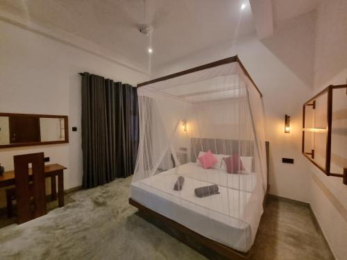 a bedroom with a canopy bed with pink pillows at Danu Surf House Hiriketiya in Dickwella