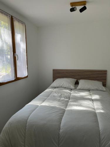un grande letto bianco in una camera da letto con una finestra di Appartement indépendant a Caussols