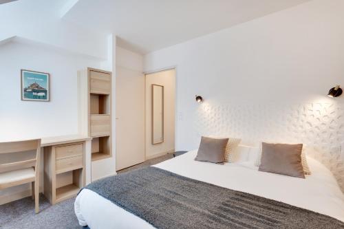 a bedroom with a large bed and a desk at Brit Hotel le Cygne in Saint-Hilaire-du-Harcouët