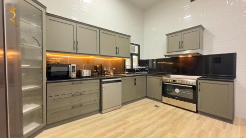 eine Küche mit Küchengeräten aus Edelstahl und weißen Schränken in der Unterkunft Luxurious Al Danah 5BR Family Friendly Getaway in Abu Dhabi