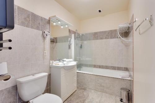a bathroom with a toilet and a sink and a tub at Brit Hotel le Cygne in Saint-Hilaire-du-Harcouët