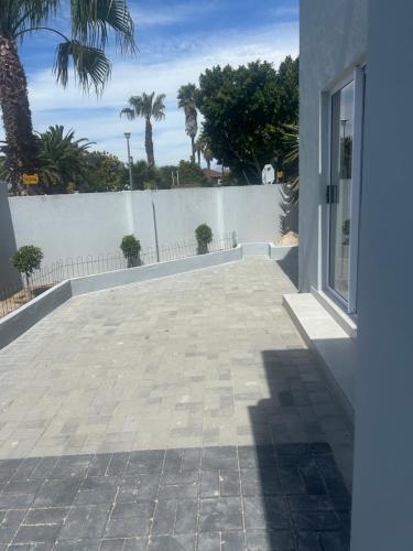 a patio of a house with a fence and palm trees at Immaculate,Alttrative &Modern 1 Noload shedding in Cape Town