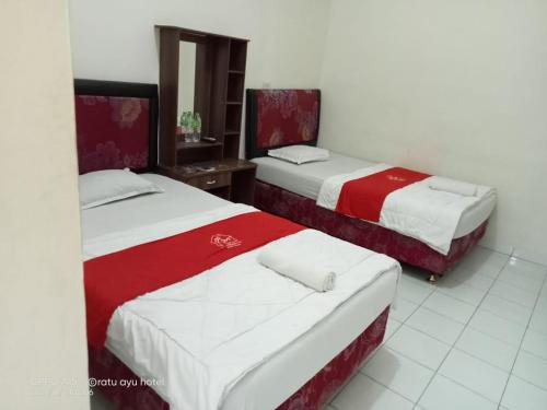 two beds in a room with red and white at Four Hostel Bandar Lampung in Tanjungkarang