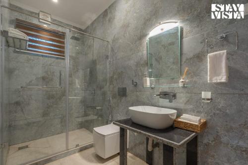 a bathroom with a sink and a glass shower at StayVista at Emaarat Chalet with BBQ & Bonfire in Srinagar