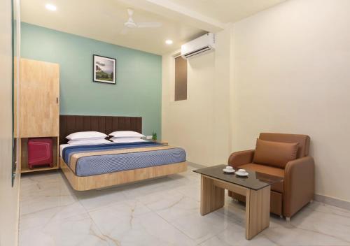 a bedroom with a bed and a chair and a table at Greens Estate Near Central Railway Station in Chennai