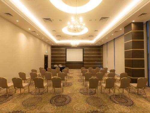 a room with chairs and a podium in front of a screen at Mövenpick Hotel Amman in Amman