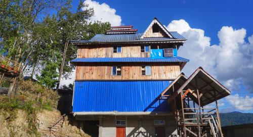 a building with a blue roof and a house at Stargaze Backpackers Ziro in Ziro