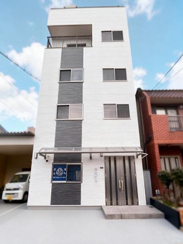 a tall white building with a car parked in front of it at 博文ビル in Osaka