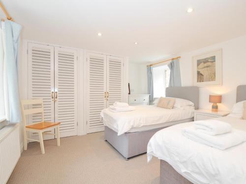 a bedroom with two beds and a chair at Orchard Cottage in Saint Endellion