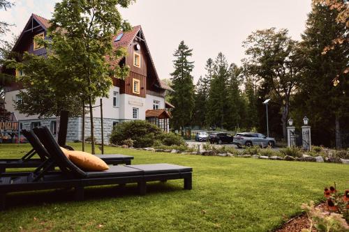 a chair sitting in the grass in front of a house at Stacja Szklarska Poręba - cisza i komfort in Szklarska Poręba