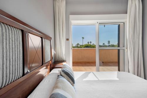 ein Schlafzimmer mit einem Bett und einem großen Fenster in der Unterkunft Chalet con Piscina Privada in Poblado de Sancti Petri