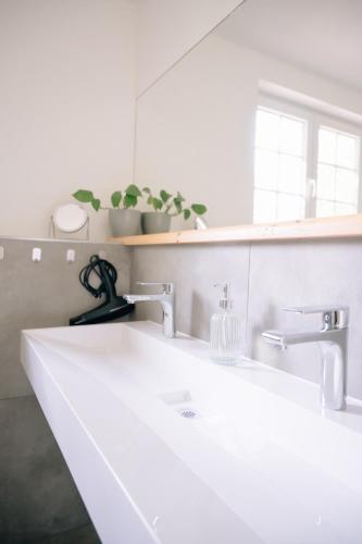 a bathroom sink with two faucets and a mirror at Ferienhaus Glücksgriff Pottenstein in Pottenstein
