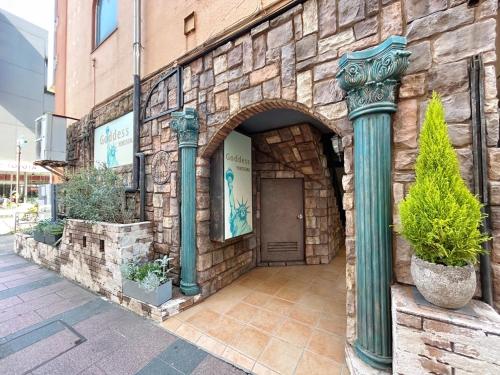 a stone building with a door and two green columns at Goddessガッデス in Yokosuka
