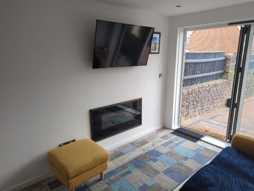 a living room with a fireplace and a tv on a wall at The Orchid in Gillingham