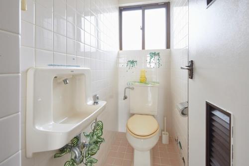 ein weißes Badezimmer mit Toilette und Waschbecken in der Unterkunft Wind Henza - Vacation STAY 73122v in Uruma