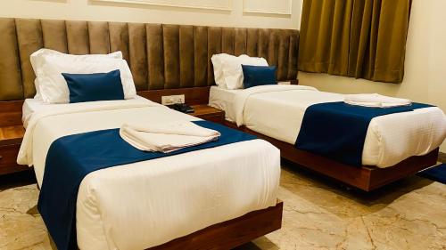 a hotel room with two beds with blue and white sheets at The Velar Hotel, Vijay Nagar in Indore