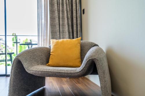 a gray chair with a yellow pillow in a room at Serenity Luxury Smart Villas with Private Pool, Canggu in Dalung