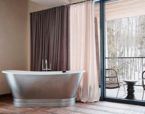 a bathroom with a tub in front of a balcony at Kokhta Bakuriani in Bakuriani
