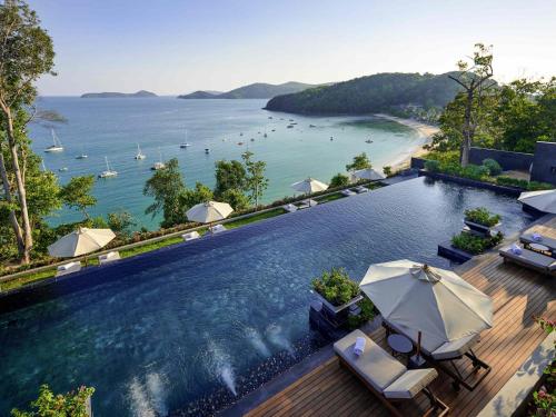 a swimming pool with umbrellas and a view of the ocean at V Villas Phuket - MGallery Collection in Panwa Beach