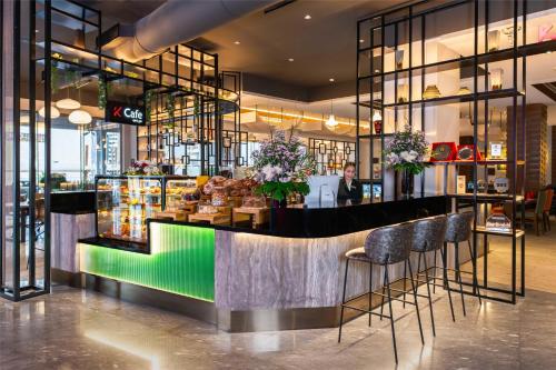 a bar in a restaurant with a woman standing behind it at The K Hotel in Manama