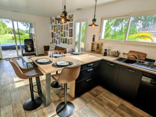 a kitchen with a wooden table with chairs and a counter at L'échappée médocaine, deux maisons indépendantes in Cussac-Fort-Medoc