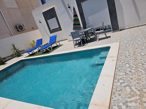 a swimming pool with chairs and a table and a umbrella at Ilef in Midoun