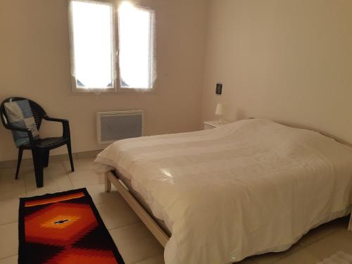 a bedroom with a bed and a chair and a window at villa soleil in Ruoms