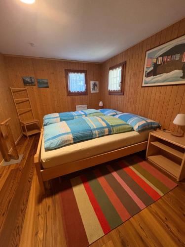 ein Schlafzimmer mit einem Bett und einem gestreiften Teppich in der Unterkunft Alter Lärch in Blatten bei Naters